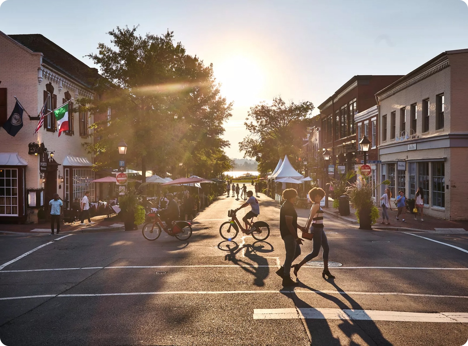 Sunset view of Old Town featured in The Link’s Alexandria neighborhood guide, with people walking and biking along King Street.
